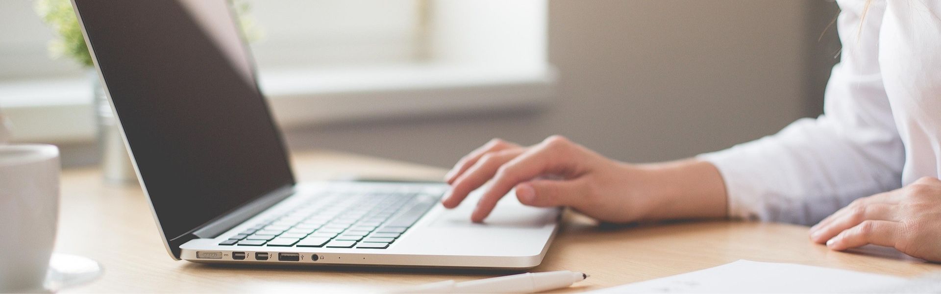 Woman typing on a grey laptop
